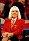 Wendy Richard, sitting with hands clasped over knee, wearing red blazer and tie, looking supremely confident, possibly from an episode of "You Bet!", from August, 1996.