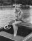Wendy Richard, wearing a bikini, stands in a motorboat
