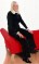 Wendy Richard, dressed in black, sitting on the arm of a red couch