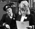 Wendy Richard as Elsie, examines some photos, to the inspector's great discomfort