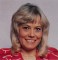 Portrait photo of smiling Wendy Richard, wearing a patterned red blouse, circa mid-1980s.